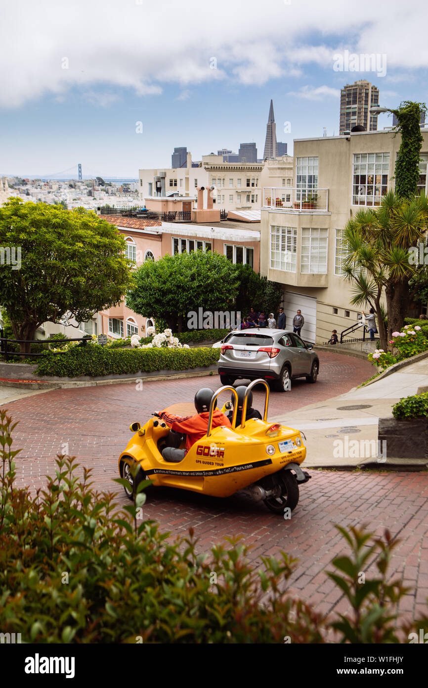 I turisti che scendono lungo la strada Lombarda con uno scooter giallo GoCar, San Francisco, California, USA Foto Stock