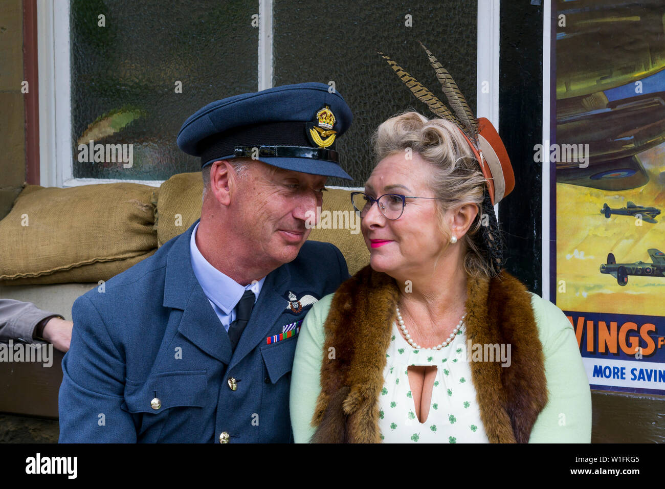 Kidderminster, Regno Unito. 29 Giugno 2019. Le ferrovie della Severn Valley 'risalenti agli anni '40' si avviano in modo favoloso questo fine settimana con i reenattori in costume che offrono un'autentica rivisitazione della Gran Bretagna in tempo di guerra della seconda guerra mondiale. Una coppia di 1940 in amore, uomo in uniforme militare RAF & donna in stile anni '40, stare amorevolmente l'uno all'altro mentre aspettano insieme, seduti insieme sulla panchina piattaforma alla stazione ferroviaria vintage. Credito: Lee Hudson Foto Stock