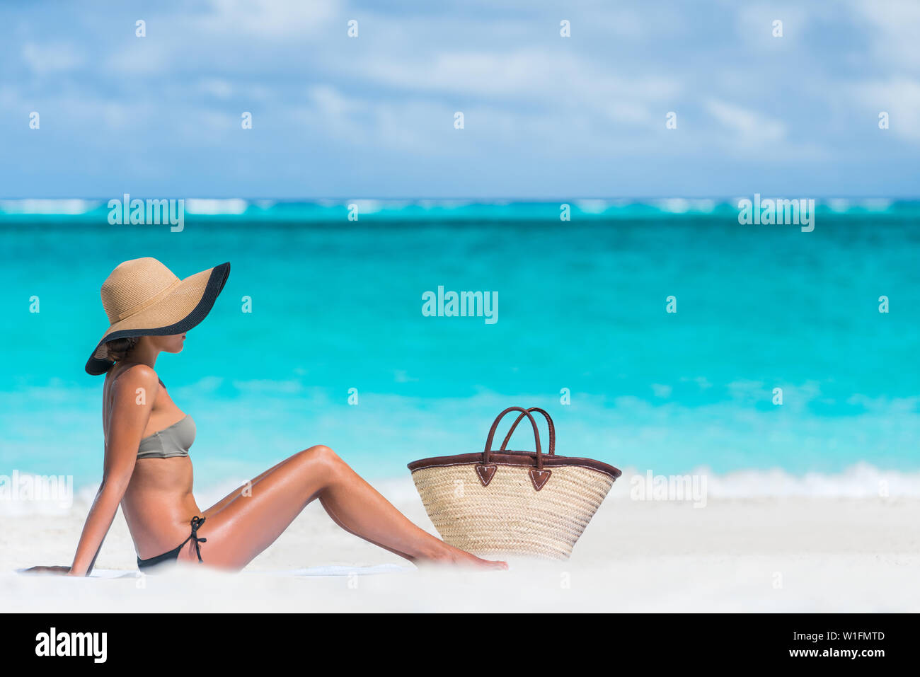 Bikini donna vacanza in spiaggia a prendere il sole in relax sulla spiaggia.  Concetto dell'abbronzatura. Irriconoscibile donna adulto godendo il sole con  cappello di paglia a prendere il sole sotto il sole