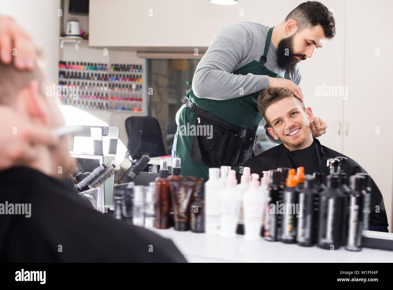 Friendly guy stilista creazione nuova forma per la barba di client al salone di parrucchiere Foto Stock