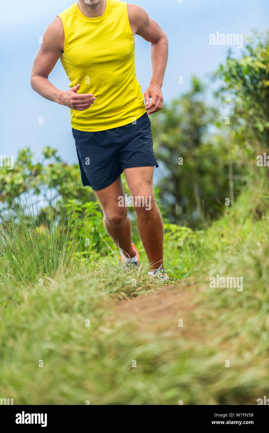 L'uomo atleta che corre al di fuori su di un percorso fitness run. Runner maschio jogging in calzature sportive sul percorso di erba che lavora fuori cardio in natura. La parte inferiore del corpo raccolto per piedi, gambe, ginocchia dolore salute sfida concetto. Foto Stock