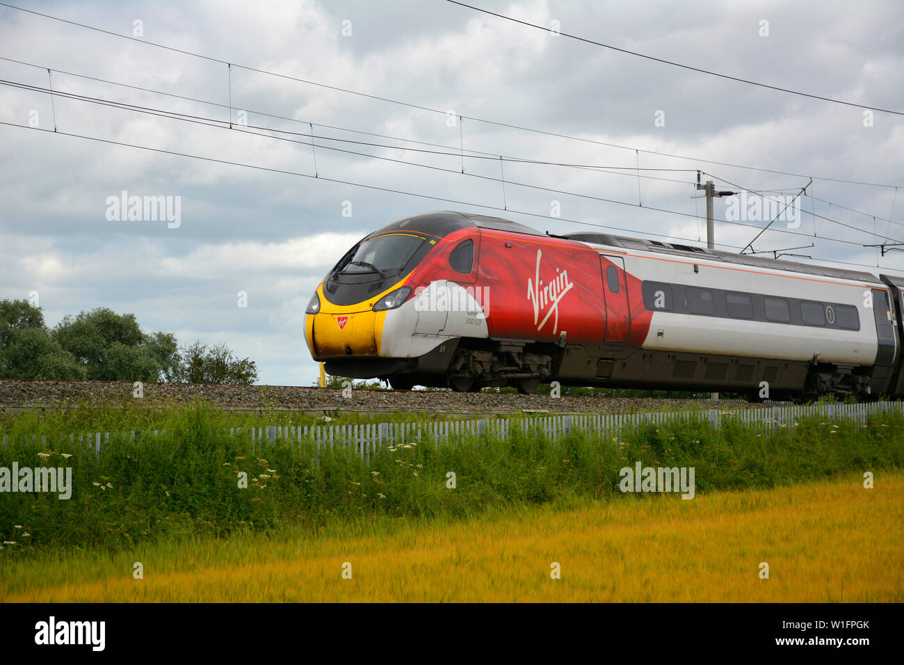 Classe vergine 390 treno pendolino sul Northampton ansa della linea principale della costa occidentale in una serata estiva Foto Stock