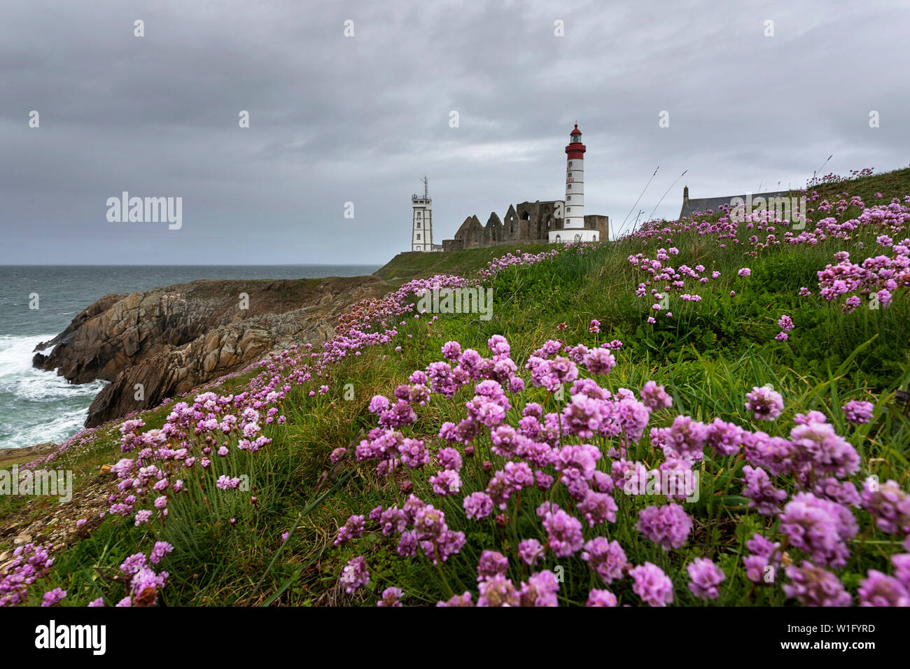 Il Lighthouse e abbey salire al di sopra del mare e coste rocciose a Pointe Saint-Mathieu in Bretagna, Francia Foto Stock