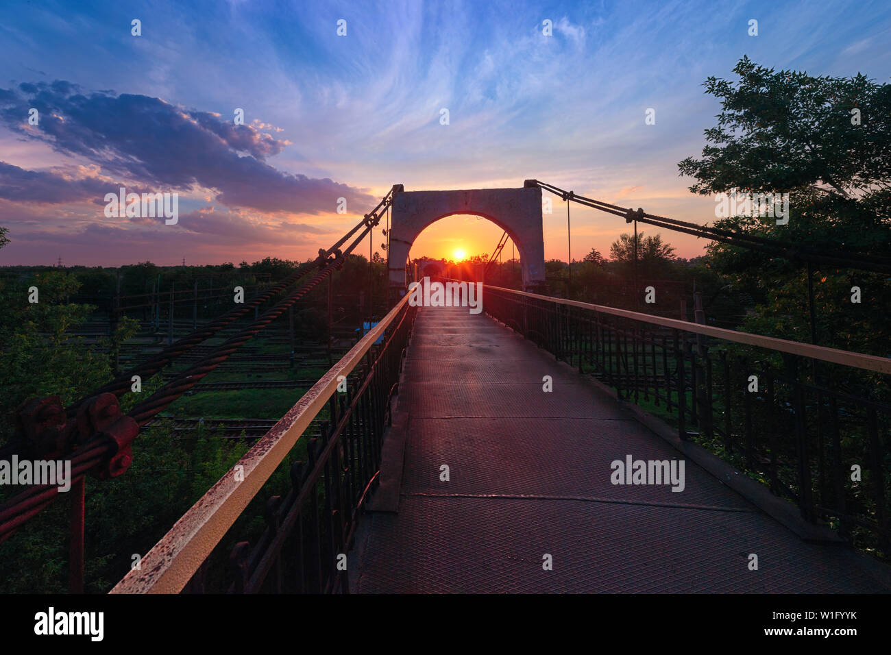 Un ponte sopra la ferrovia su un bellissimo luminoso Nuvoloso Tramonto sfondo in Krivoy Rog, Ucraina Foto Stock