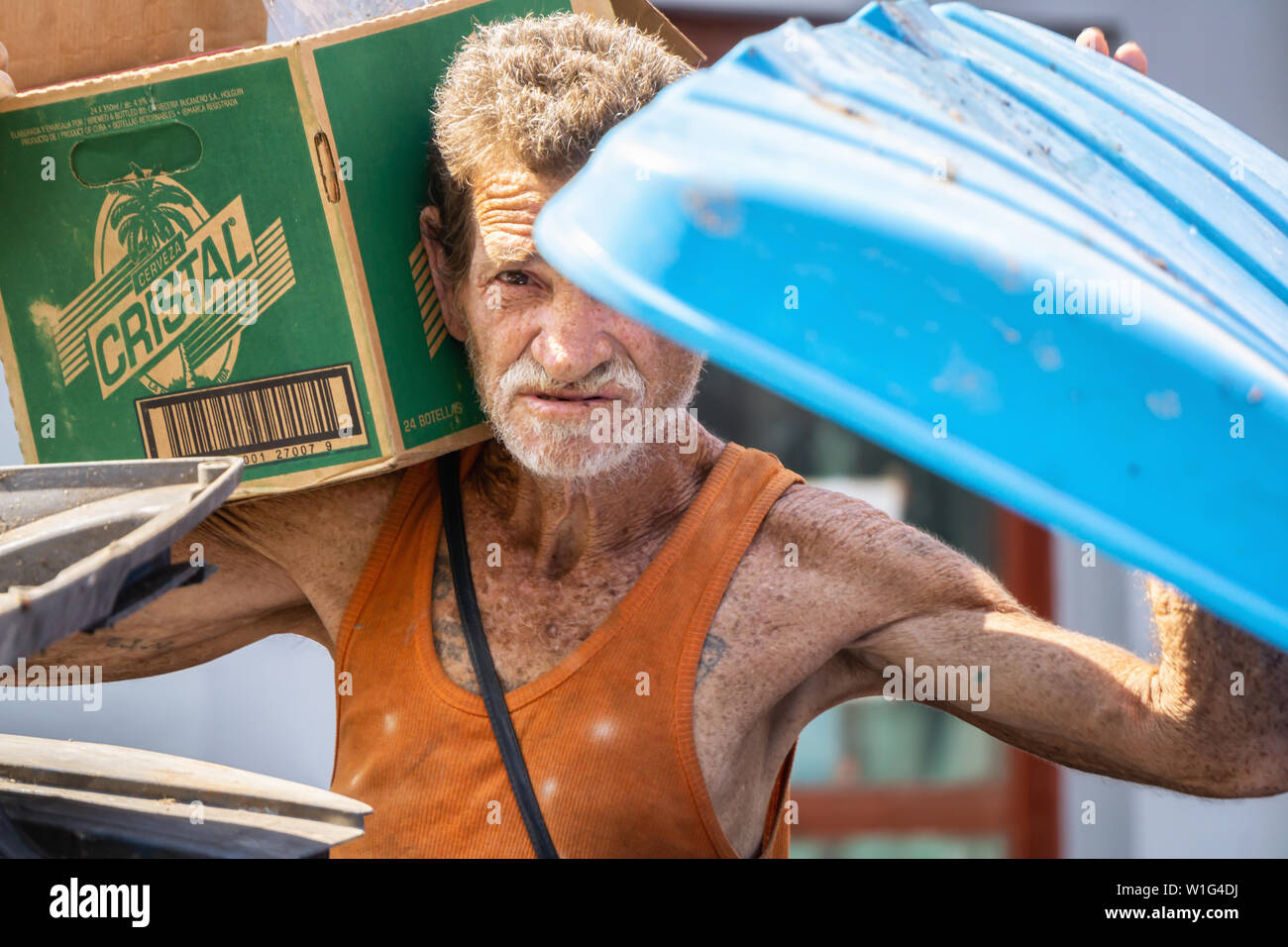 L'Avana, Cuba - Maggio 17, 2019: vecchi e sporchi senzatetto cubano uomo sta cercando nel bidone della spazzatura per le strade della vecchia Havana City durante una calda giornata di sole. Foto Stock