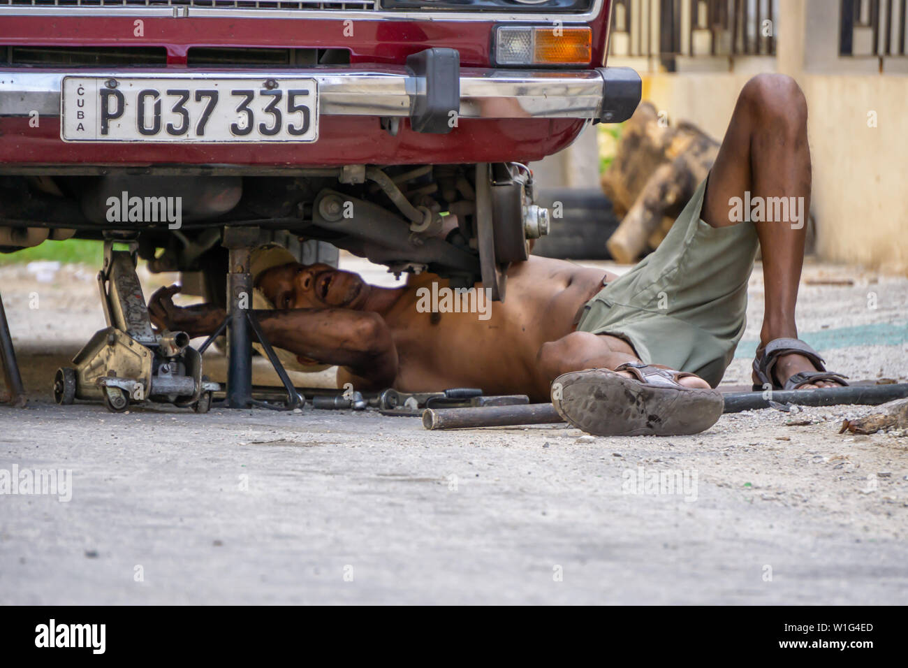 L'Avana, Cuba - Maggio 17, 2019: Sporco auto cubano meccanico è lavorare sotto il veicolo per le strade della vecchia Havana City durante una calda giornata di sole. Foto Stock