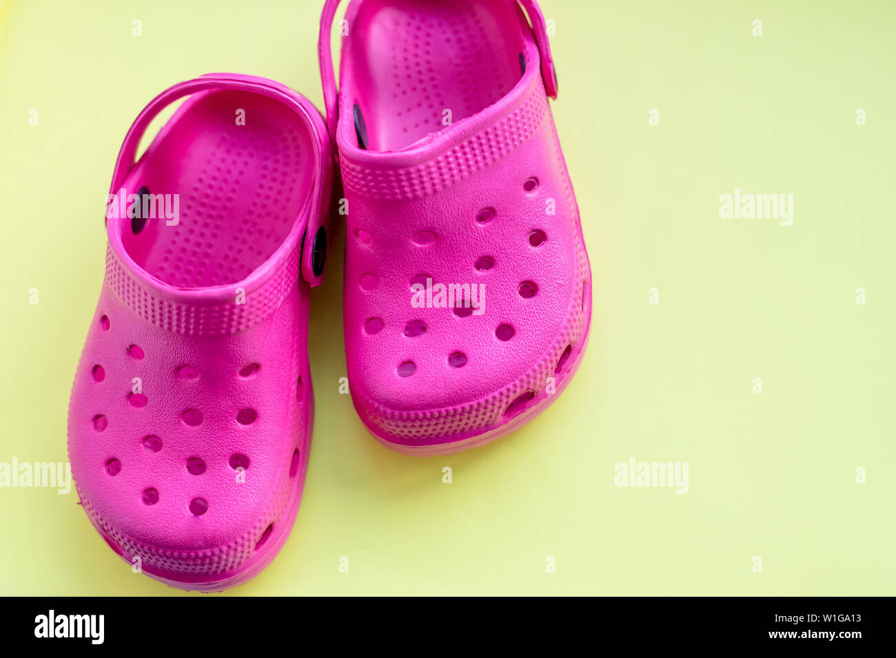 San Diego, Stati Uniti d'America,10 Maggio 2019.Estate rosa flip flop isolato su sfondo giallo. Bambini in gomma morbida o sandali Crocs.vacanze estive Scarpe alla moda Foto Stock