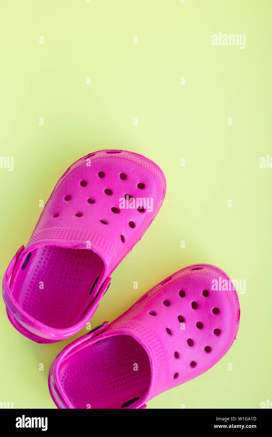 San Diego, Stati Uniti d'America,10 Maggio 2019.Estate rosa flip flop isolato su sfondo giallo. Bambini in gomma morbida o sandali Crocs.vacanze estive Scarpe alla moda Foto Stock