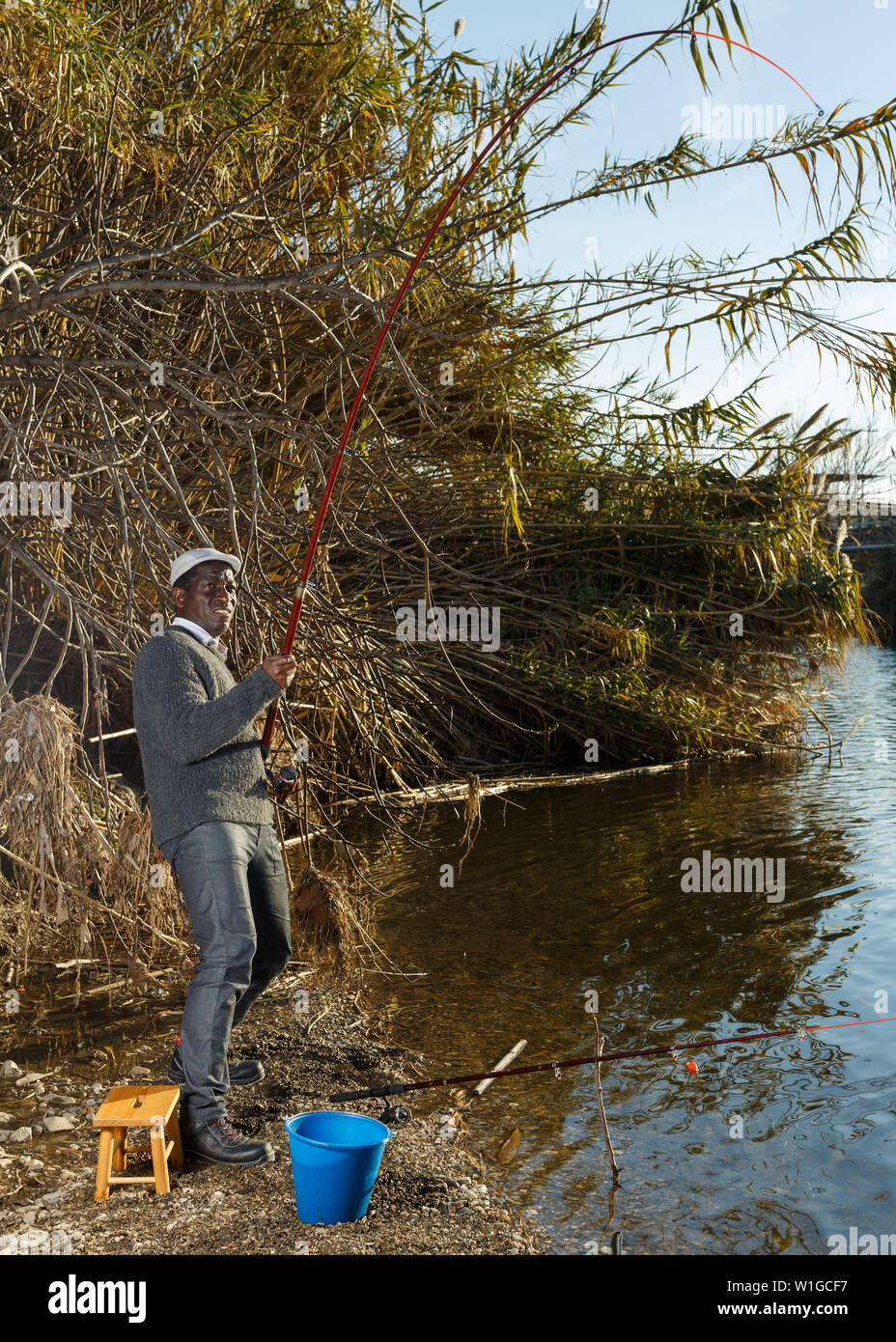 Emotional ritratto di uomo africano tirando con asta di pescare sul fiume Foto Stock