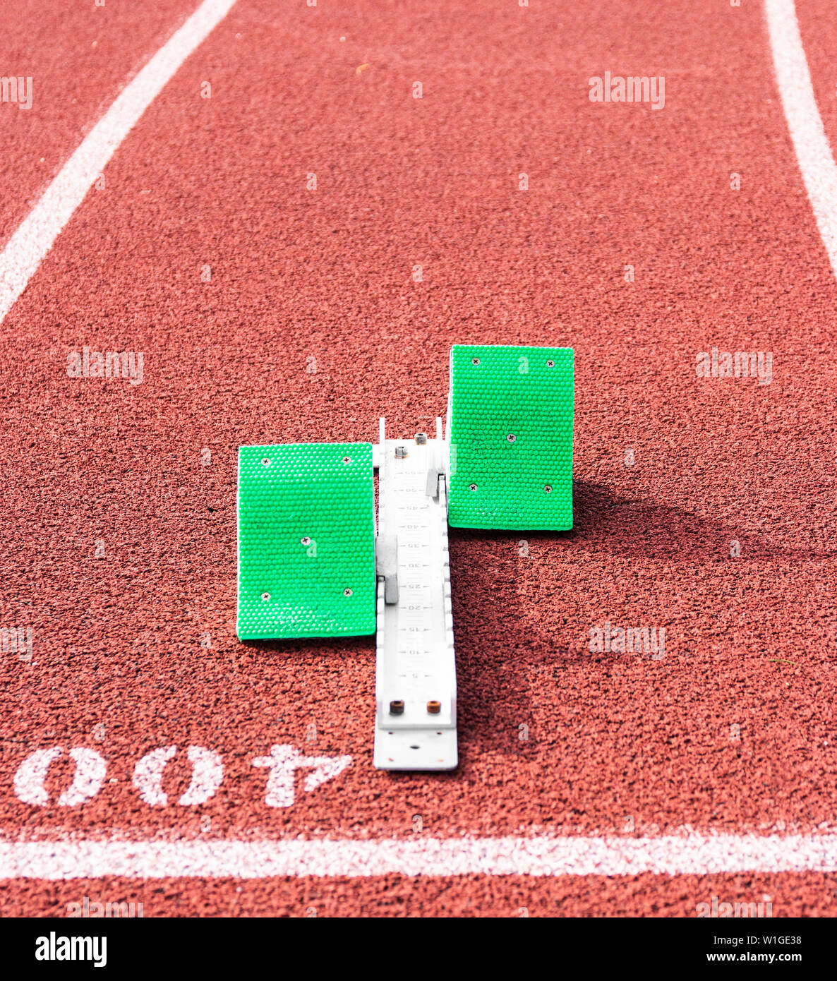 Un set di verde i blocchi di partenza è pronta per essere utilizzata a 400 metri la linea di partenza su una pista rossa. Foto Stock