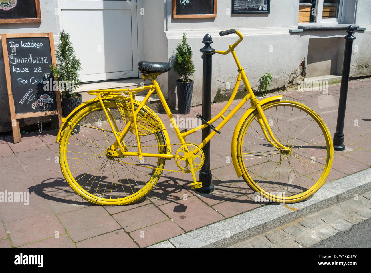 Una bicicletta d'epoca dipinta di giallo all'esterno di un caffè Cracovia, Polonia, Europa. Foto Stock