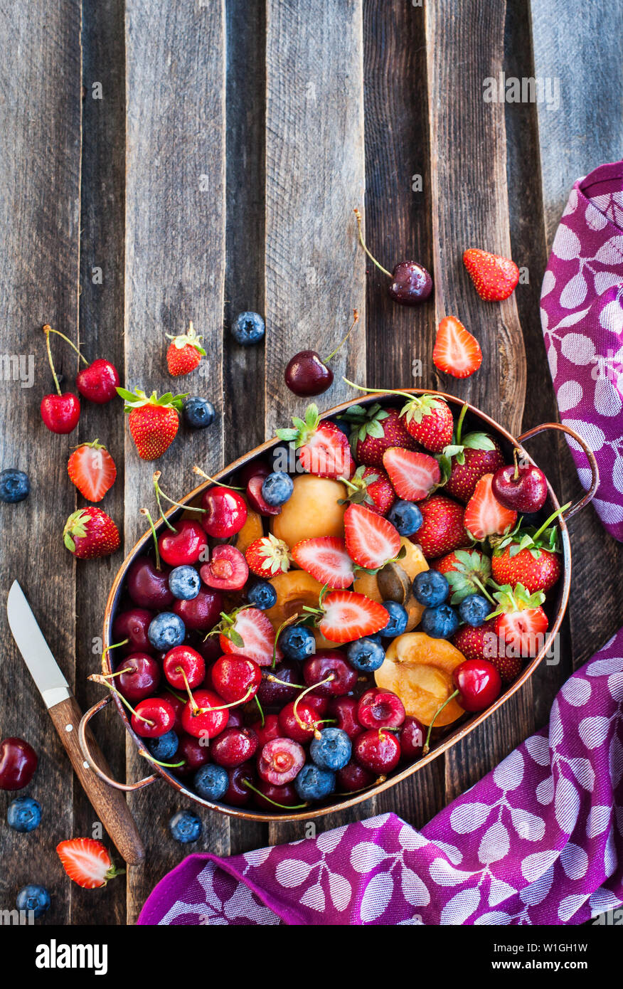Matura fresca estate di bacche e frutti (ciliegia, fragola, mirtillo, albicocche) su legno rustico sfondo, vista dall'alto Foto Stock