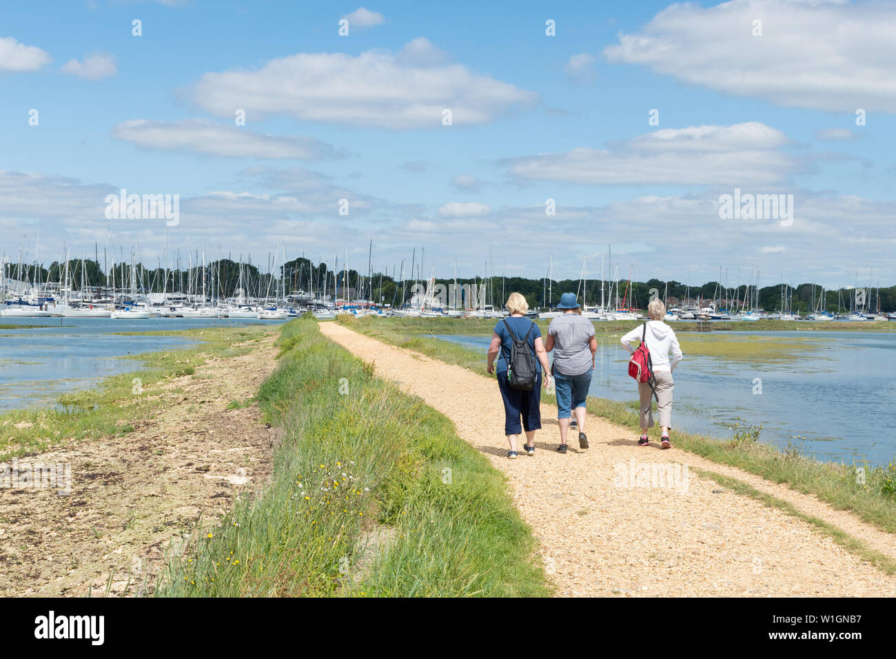Tre donne camminando lungo il Solent modo a lunga distanza percorso accanto al fiume Hamble su una soleggiata giornata estiva, Hampshire, Regno Unito Foto Stock