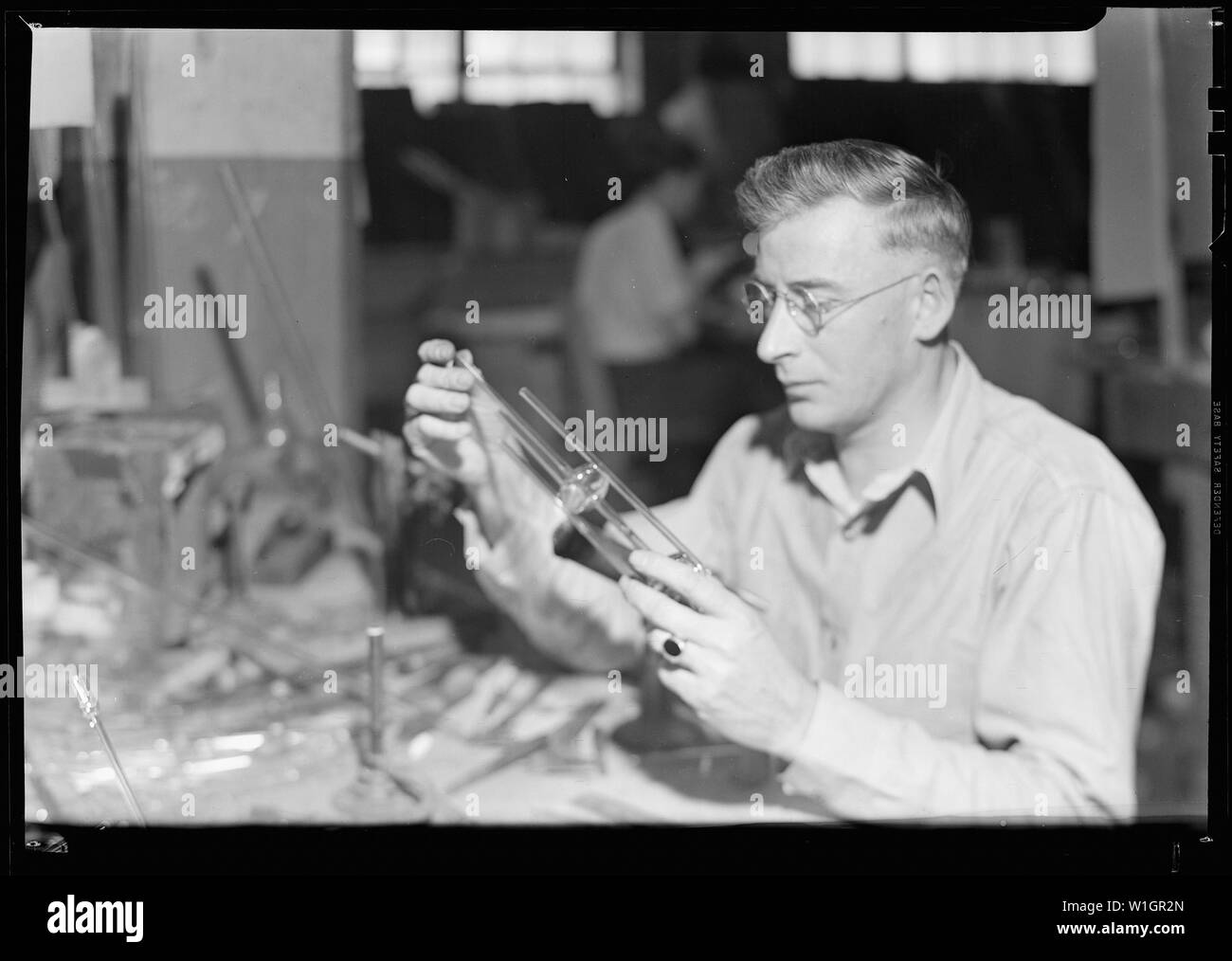 Millville, nel New Jersey - Bottiglie in vetro. L. G. Nestor Co. Tubo di soffiaggio del lavoratore cella di conducibilità. Questo altamente esperto lavoratore prende il tubo di vetro e la soffia in forme complesse necessarie per chimico ware. Egli utilizza stampe blu nel determinare le dimensioni delle bottiglie egli soffia. Il vetro viene riscaldato pronto per soffiare via la piccola fiamma a gas illustrato a sinistra al centro dell'immagine. Foto Stock