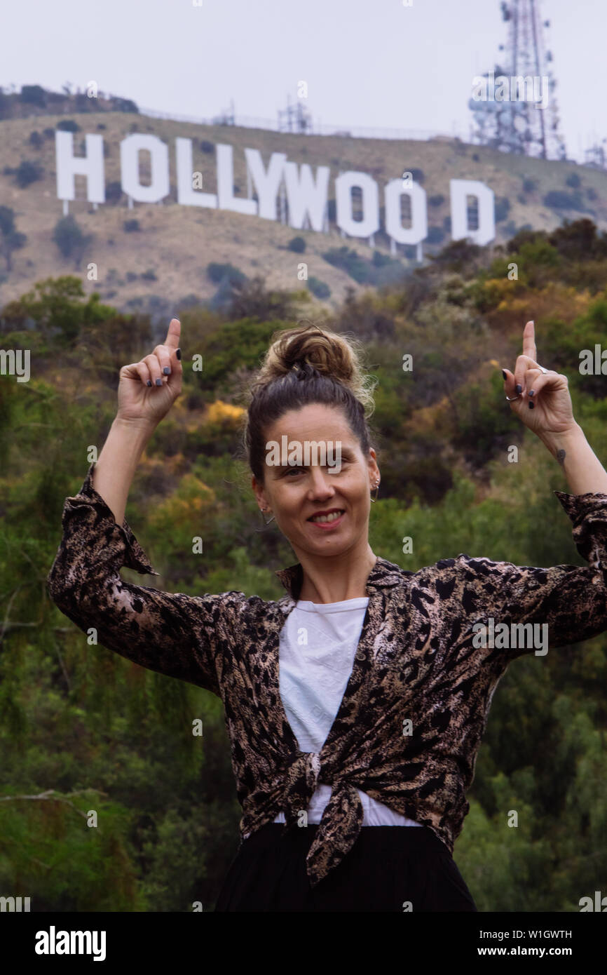 Donna turistica in posa e indicando con le dita verso il segno di Hollywood e Los Angeles, California, Stati Uniti d'America Foto Stock
