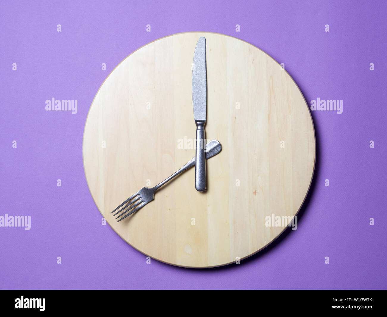 Il digiuno intermittente e saltare la colazione concetto - svuotare la rotonda di legno o vassoio scavatrincee con posate come mani di orologio su sfondo lilla. Otto ore di finestra di avanzamento di un concetto o di prima colazione il concetto di tempo Foto Stock Il digiuno intermittente e saltare la colazione concetto - svuotare la rotonda di legno o vassoio scavatrincee con posate come mani di orologio su sfondo lilla. Otto ore di finestra di avanzamento di un concetto o di prima colazione il concetto di tempo Foto Stock