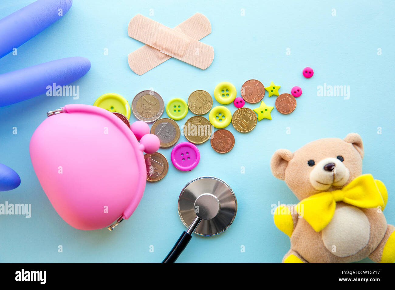 Bambini e denaro nel sistema sanitario. Monete e simpatici i pulsanti colorati sul lato del denaro rosa borsa, uno stetoscopio, batch, guanto di gomma palloncino, fla Foto Stock