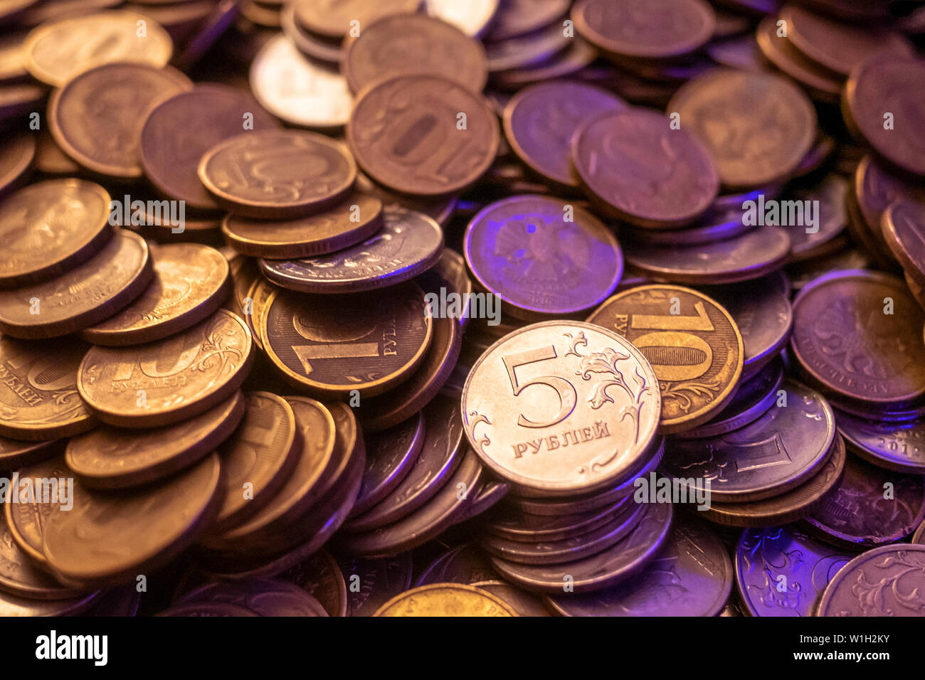 Una manciata di monete d oro e d argento in una luce violetta. una manciata  di monete di rubli nel buio luce Foto stock - Alamy