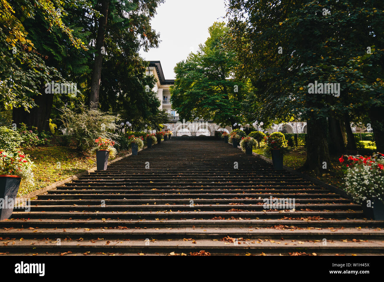 Bled, Slovenia - settembre, 8 2018: la scala che porta al Lago di Bled dal retro del Vila Bled hotel con foglie che cadono, circondato da alberi e flowe Foto Stock