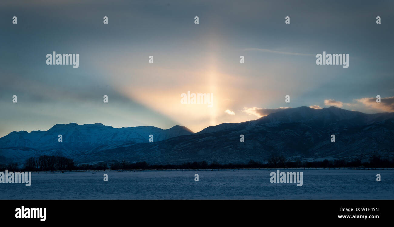 Il sole di setting spara raggi nel cielo invernale sul monte Timpanogos vicino a Midway, Utah. (C) 2013 Tom Kelly Foto Stock