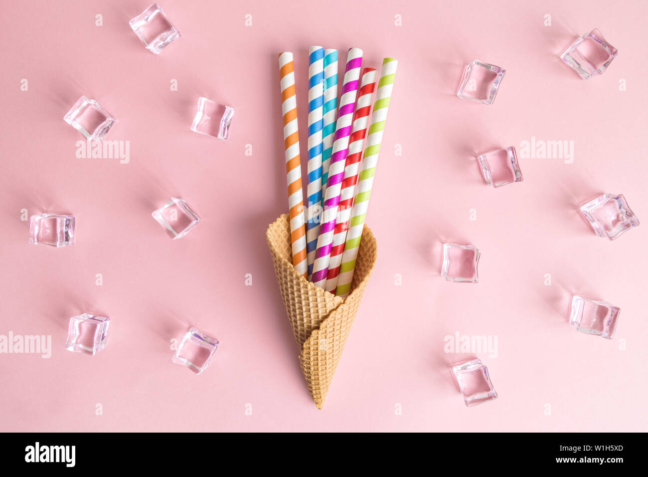 Cono gelato con colorati di bere cannucce e cubetti di ghiaccio su rosa luminoso dello sfondo creative minimo il cibo e le bevande del concetto. Foto Stock