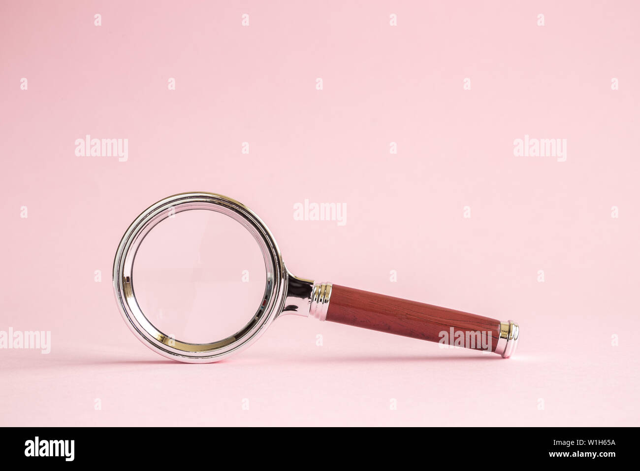 Retrò lente di ingrandimento contro di rosa pastello minima di sfondo concetto creativo. Spazio per la copia. Foto Stock