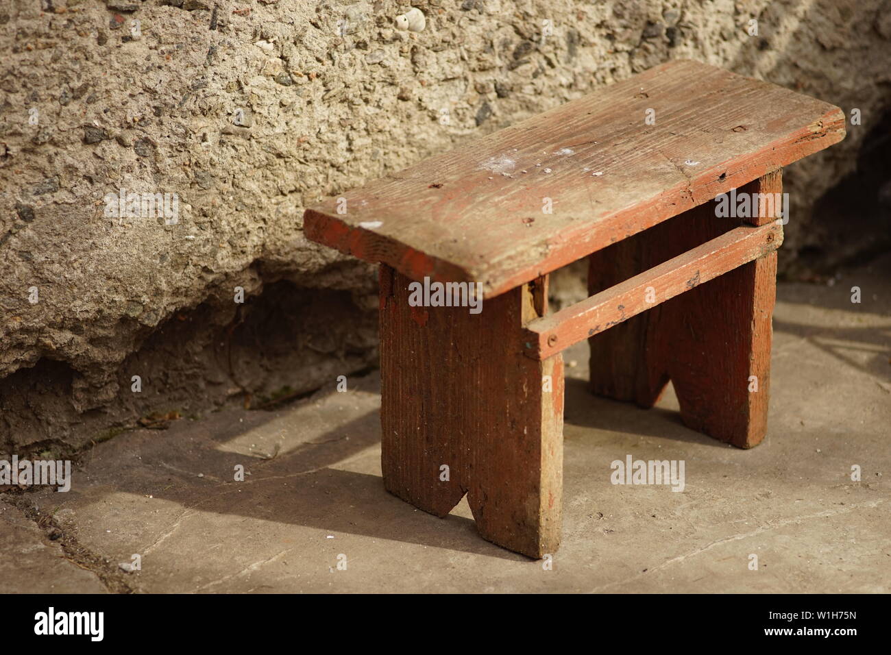 Il vecchio legno bruno Sgabello basso in cantiere con la luce solare Foto Stock