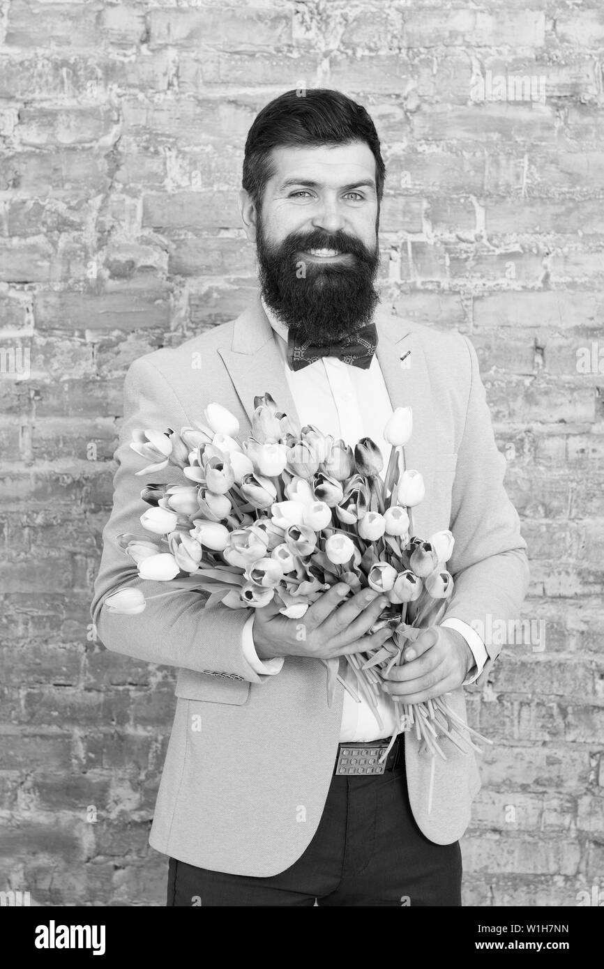 Uomo romantico con fiori. Regalo romantico. Macho getting ready data romantico. In attesa di Darling. I tulipani per sweetheart. L'uomo ben curato usura tuxedo bow tie tenere bouquet di fiori. Invitatela dating. Foto Stock