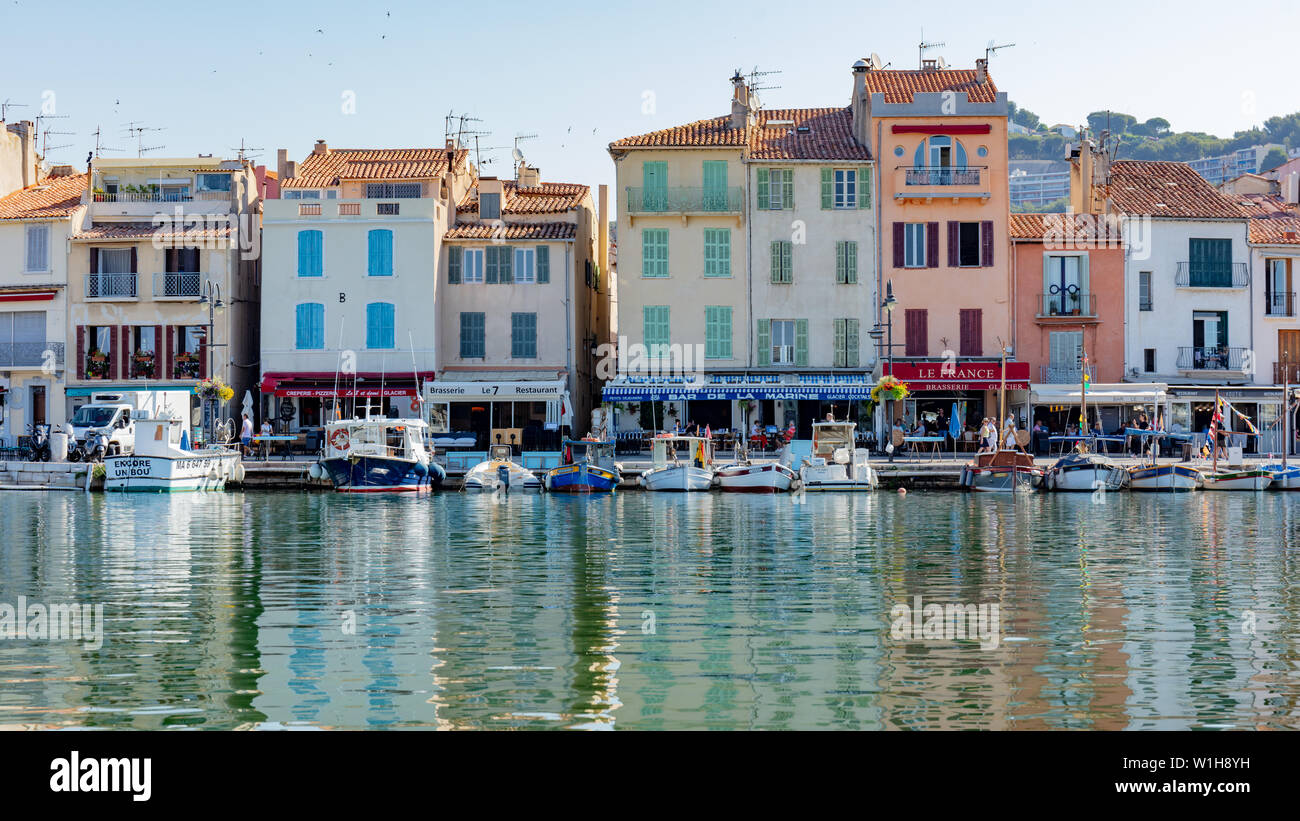 Cassis, Francia; 22 giugno 2019; linea di barche da pesca ormeggiate con i suoi edifici colorati dietro Foto Stock
