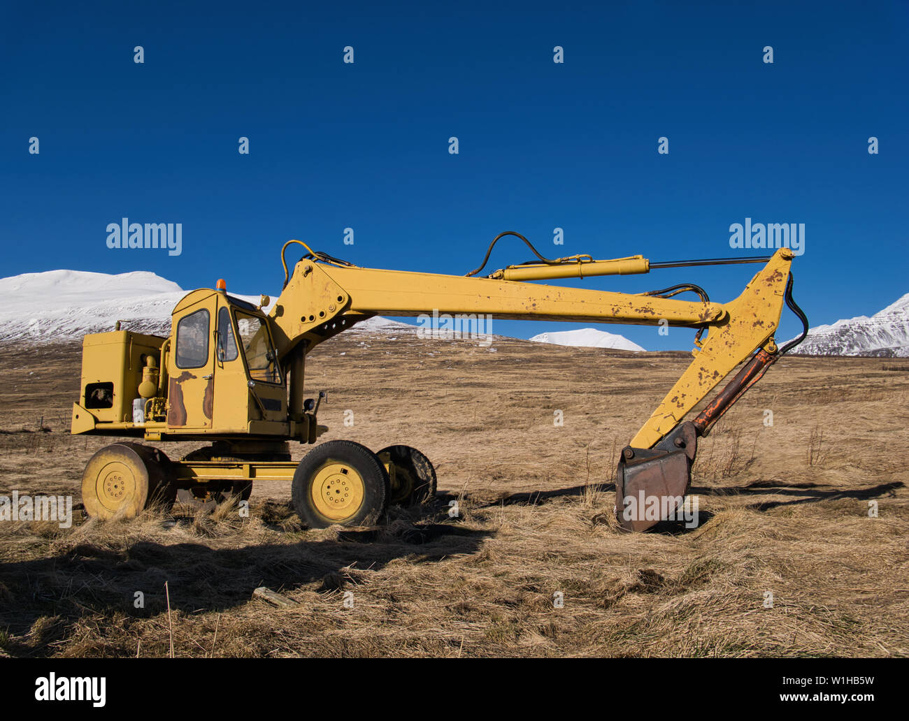 Un vecchio giallo digger era parcheggiata nel mezzo di un prato in Islanda Foto Stock