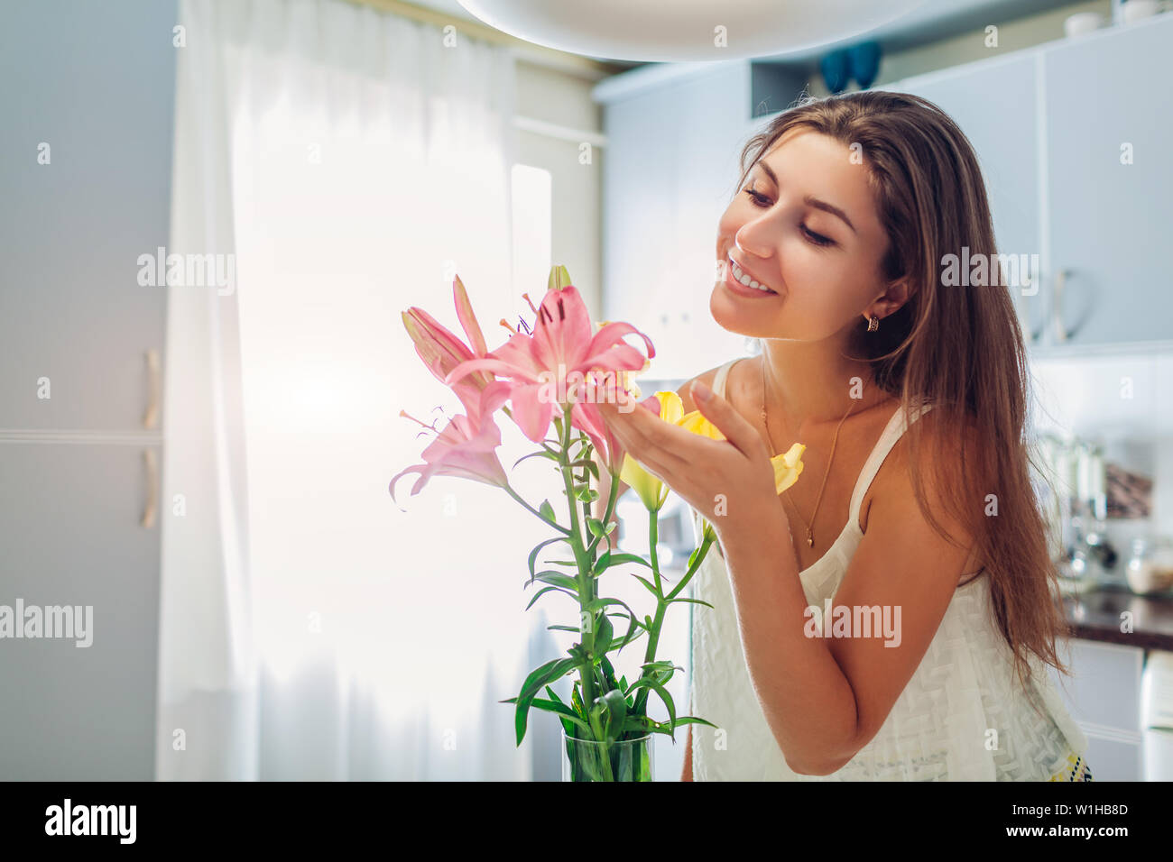 Donna felice odore di profumo di gigli. Casalinga godendo di arredamento di interni e di cucina. Sweet home. Allergy free Foto Stock