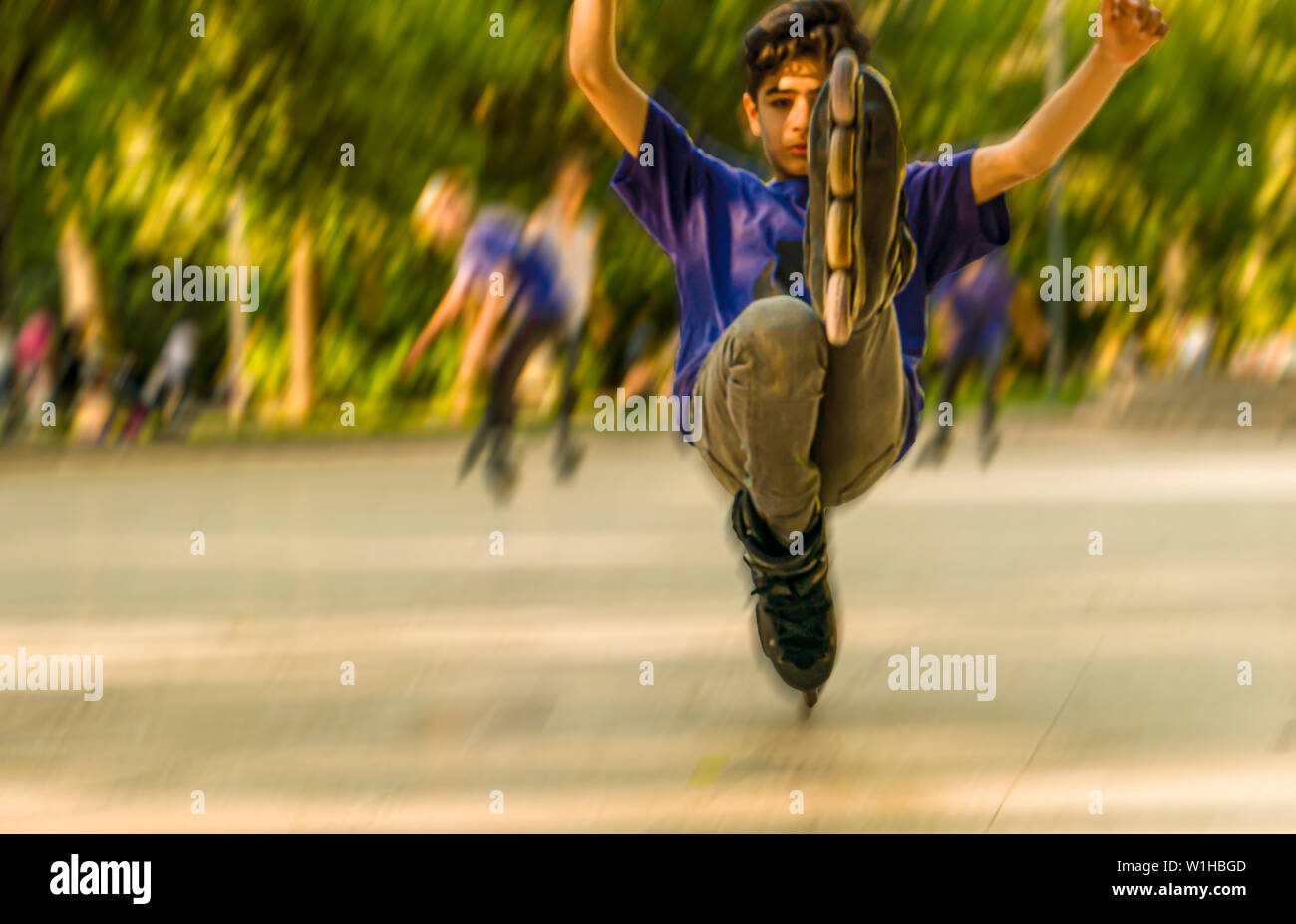 Ankara/Turkey-June 23 2019: Abstract sfocato boy gioca il trucco su pattini a rotelle. Corse su una gamba in uno squat Foto Stock