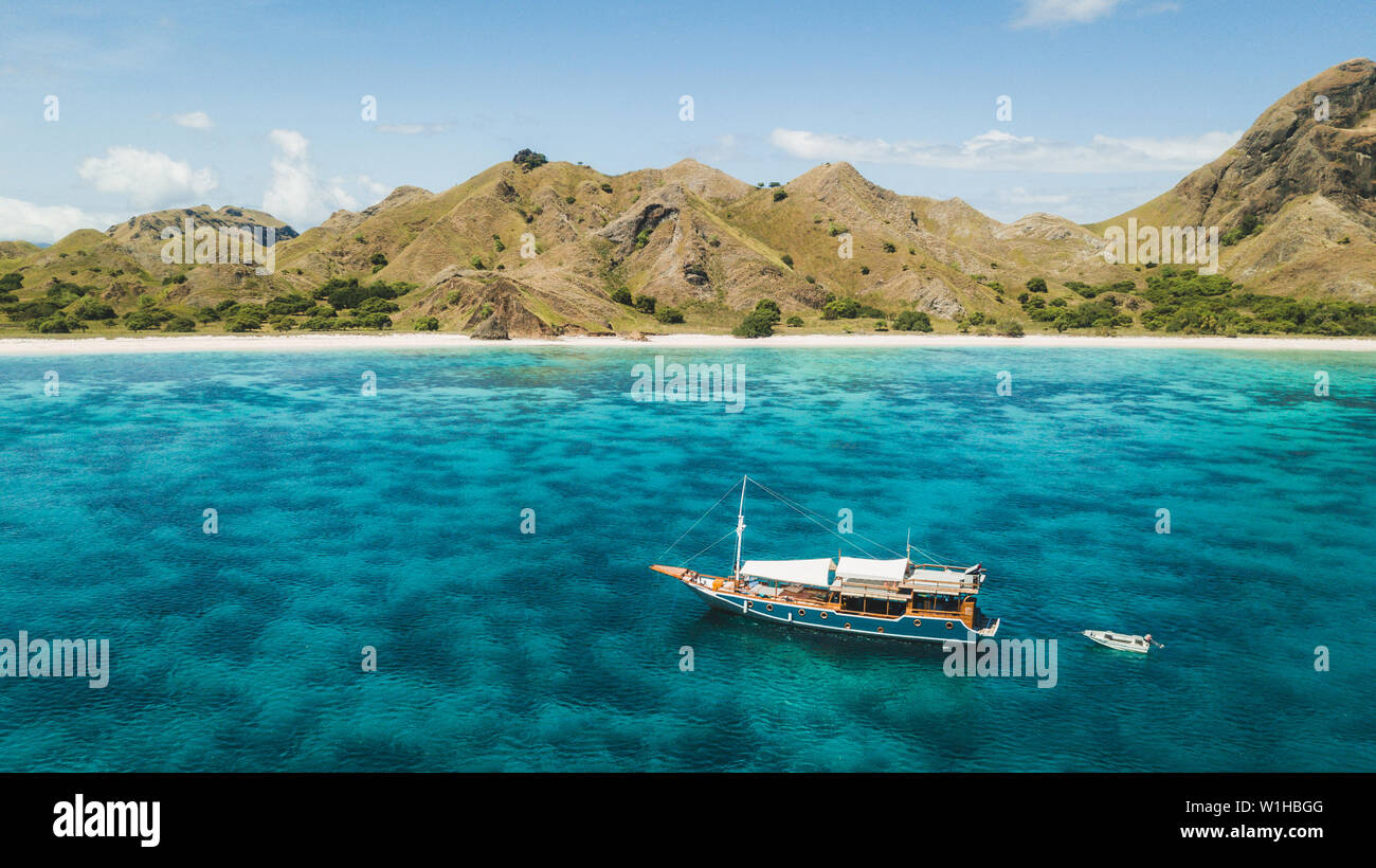 Crociera di Lusso in barca a vela sulla barriera corallina con incredibile spiaggia tropicale e vista sulla montagna. Vista aerea. Isola di Padar, Komodo Indonesia. Foto Stock