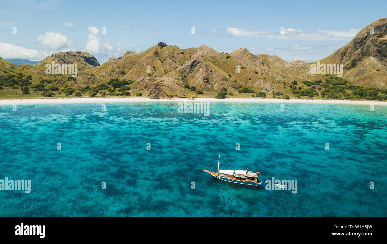 Crociera di Lusso in barca a vela sulla barriera corallina con incredibile spiaggia tropicale e vista sulla montagna. Vista aerea. Isola di Padar, Komodo Indonesia. Foto Stock