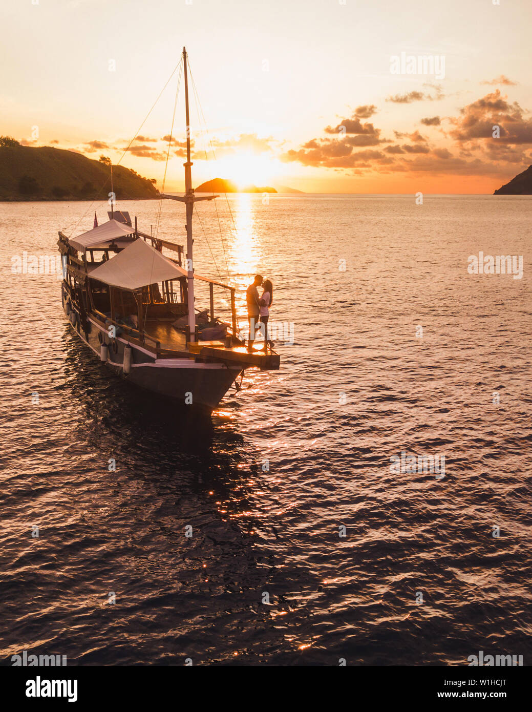 Giovani hippie matura in amore godersi il tramonto sulla scheda di yacht, antenna fuco vista. Marine e di viaggio isola tropicale concetto di crociera. Foto Stock