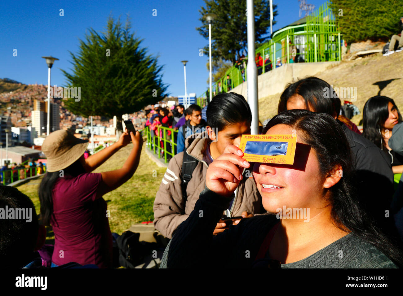 La Paz, Bolivia 2 Luglio 2019: una donna usa un eclissi solare filtro per guardare un'Eclissi Parziale di Sole a un'eclisse guarda caso vicino al centro della citta'. In La Paz la eclipse è durato per circa 2 ore e 10 minuti con circa il 55% di copertura al suo massimo. Foto Stock