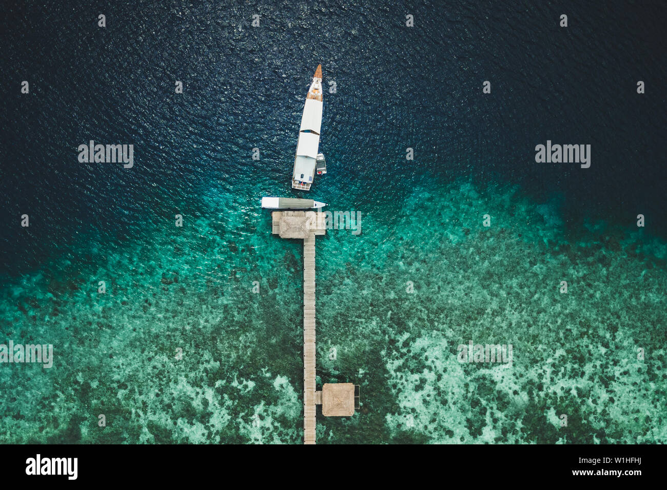 Vista aerea del molo con yacht su isola tropicale con barriera corallina costiera. Crociera e barca di lusso concetto di viaggio. Direttamente dal di sopra. Foto Stock