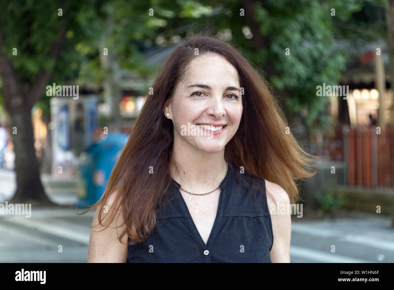 Ritratto di una donna matura, 40s, sorridente guardando la fotocamera all'aperto in una città. Foto Stock