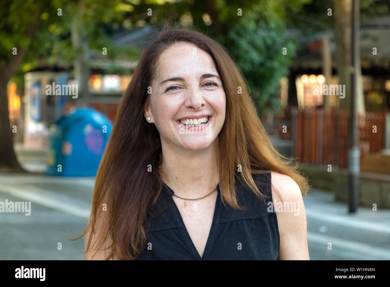Ritratto di una donna matura, 40s, felici di ridere guardando la fotocamera all'aperto in una città. Foto Stock
