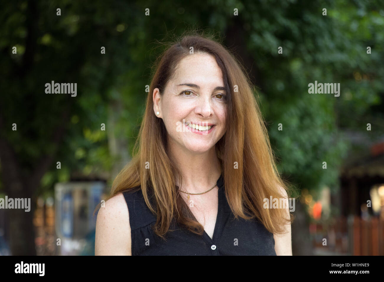 Ritratto di una donna matura, 40s, sorridente guardando la fotocamera all'aperto in una città. Foto Stock