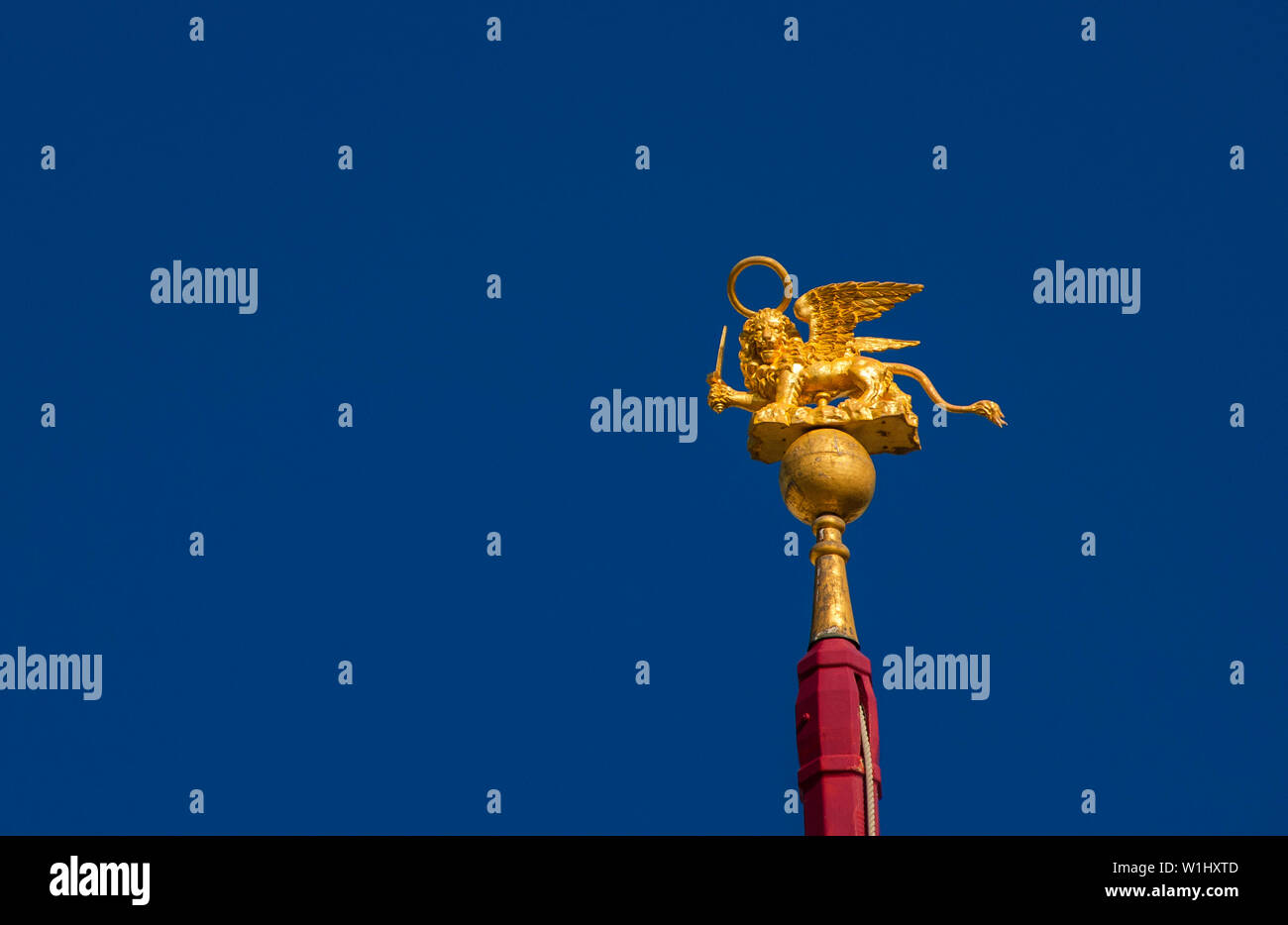 San Marco leone alato golden statuetta brandendo una spada contro il cielo blu, un simbolo della Vecchia Repubblica di Venezia in guerra (con copia spazio) Foto Stock