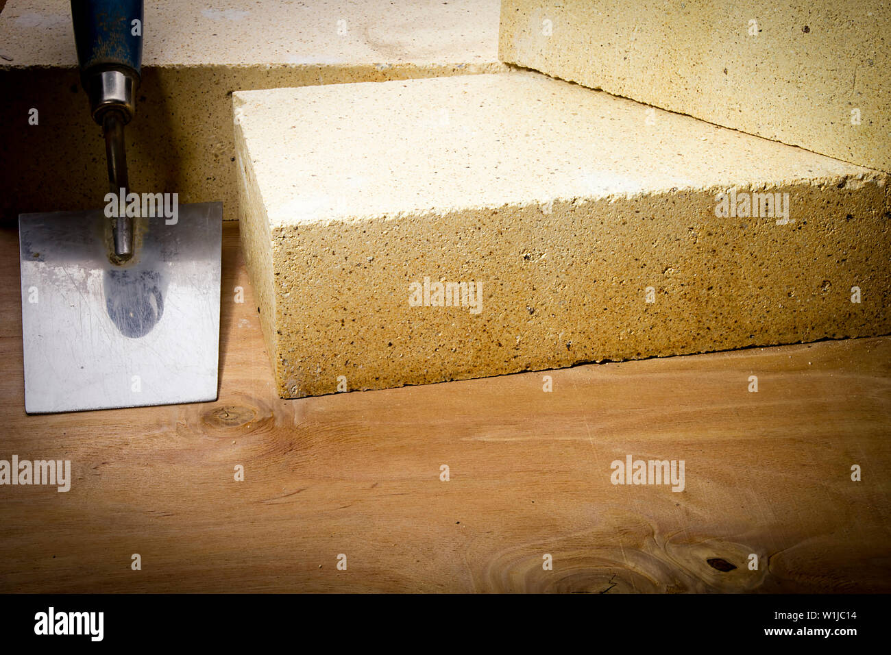 Fire mattoni e frattazzo su una superficie in legno Foto Stock