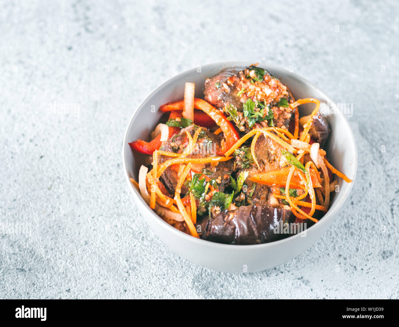 Insalata di melanzane sott'aceto, la carota, la cipolla e il peperone in ciotola sul cemento grigio Sfondo. Alimento fermentato. Conserve di ortaggi. Copia spazio per il testo. Foto Stock