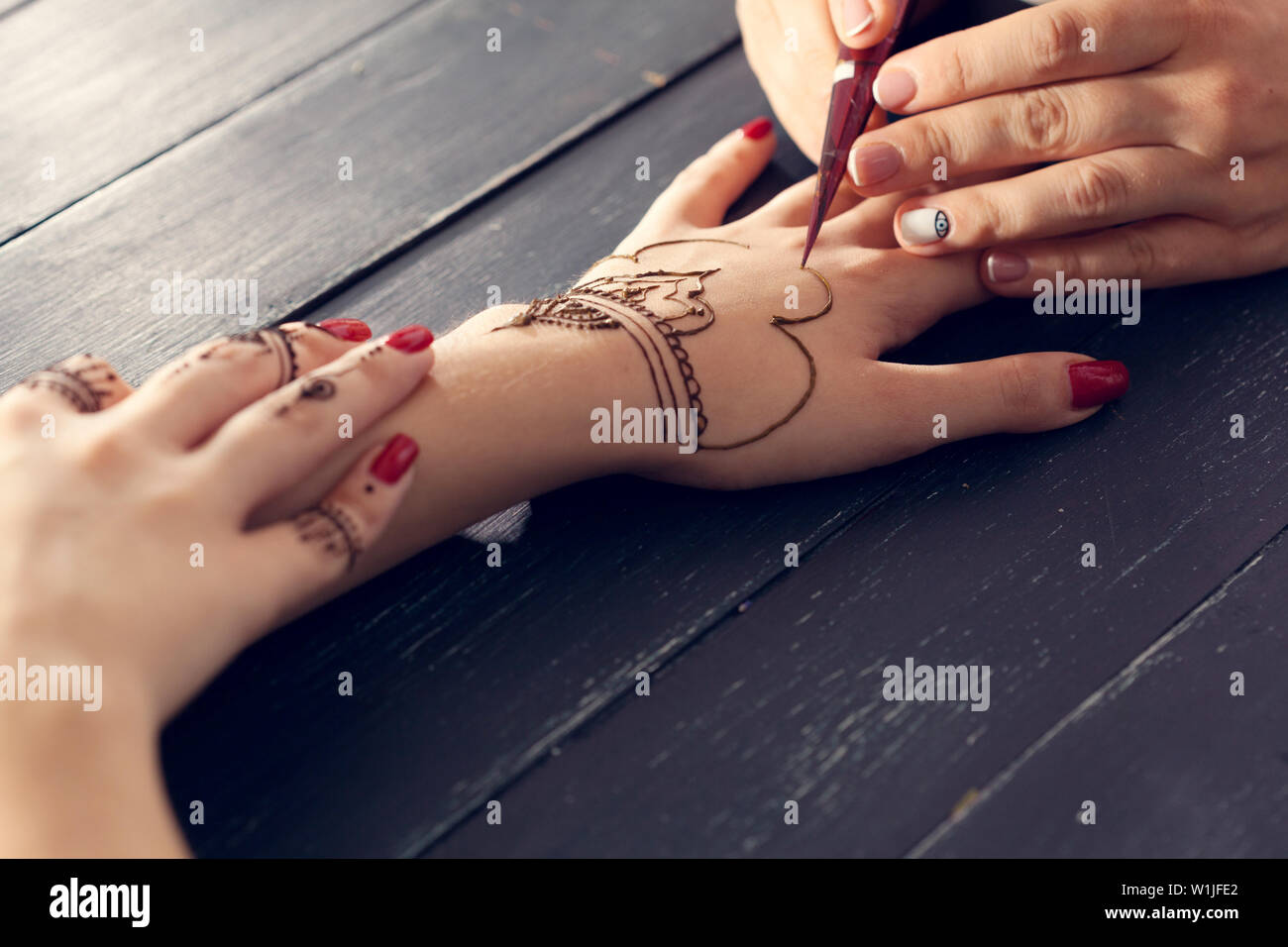 Il processo di applicazione della mehndi sulle mani femminili Foto Stock