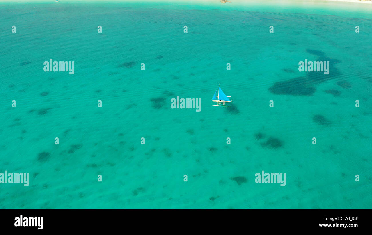 Sailing yacht in cristalline acque turchesi, vista aerea. Barca a vela scivola sulle onde, Boracay, Filippine. Foto Stock