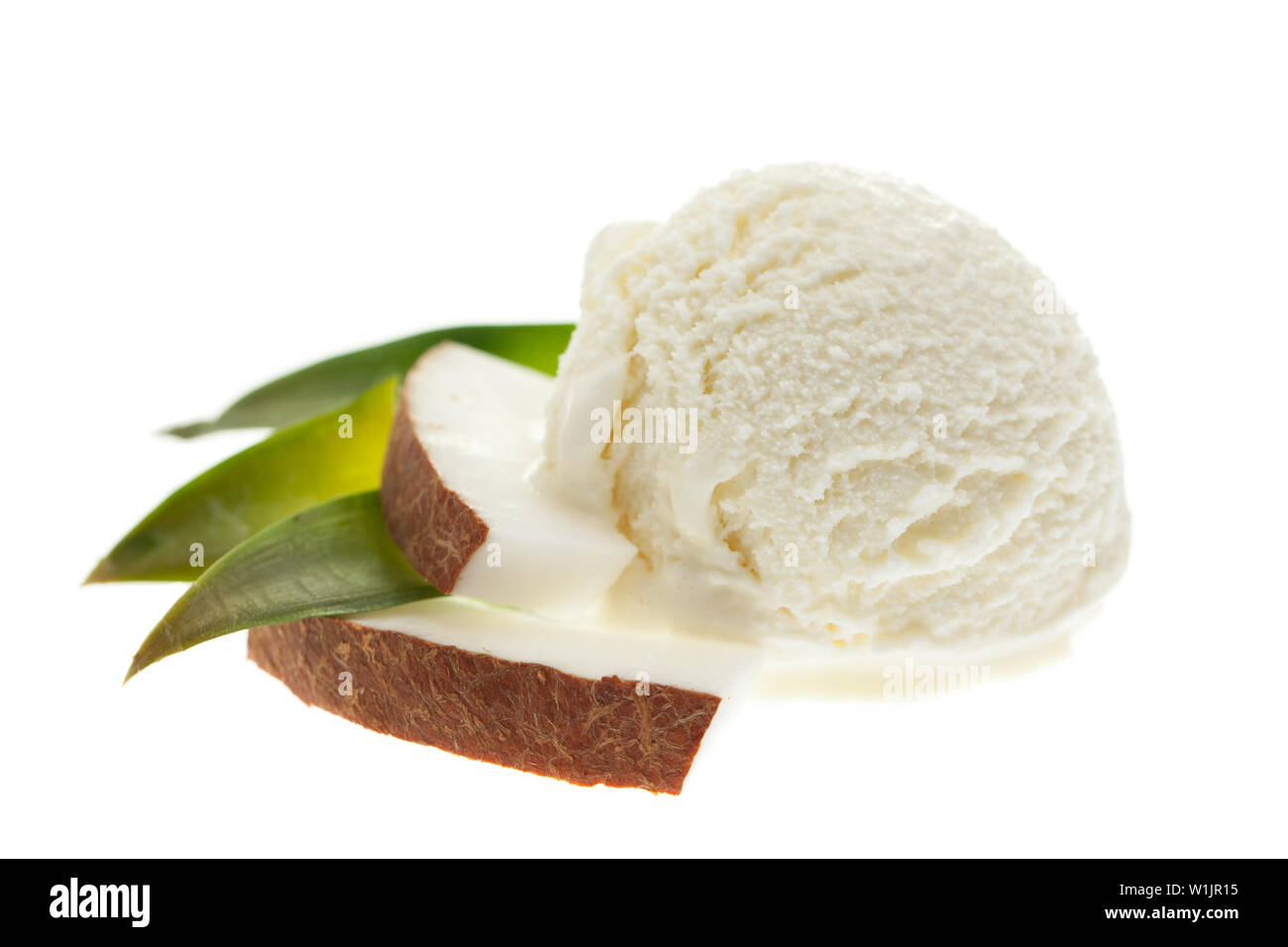 Un cucchiaio di noce di cocco gelato con foglie e fette di noce di cocco isolati su sfondo bianco Foto Stock