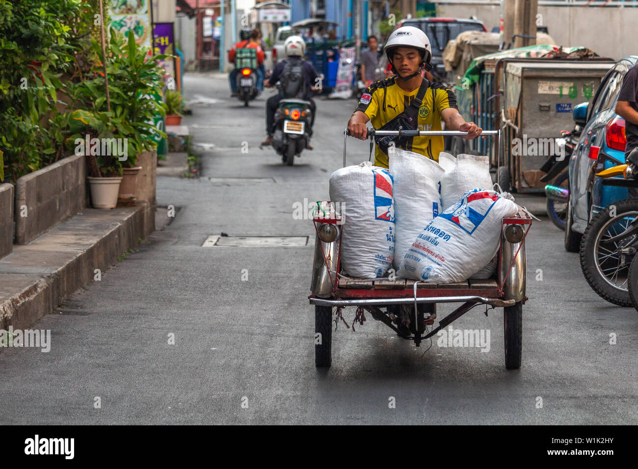 Bangkok, Tailandia - 12 Aprile 2019: Giovane ragazzo il trasporto di merci su una vecchia autovettura per le strade di Bangkok Foto Stock