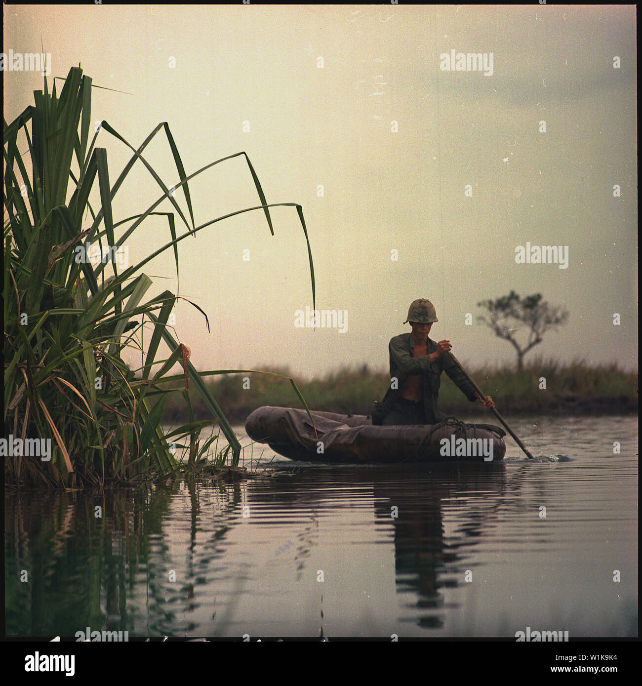 Il Vietnam. Privato di prima classe David Sletten, medic, la società B, !st battaglione di fanteria 27, XXV divisione di fanteria, palette, una tre-uomo assalto barca lungo il canale verso un punto di rottura durante il funzionamento Tong Thang I. Foto Stock