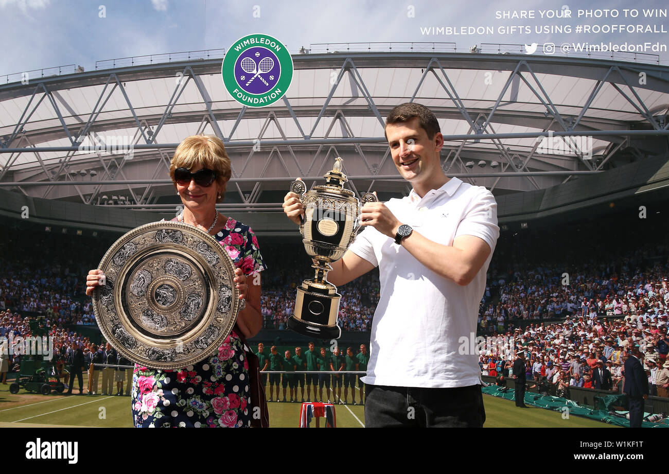 Gli spettatori posano con tagli di cartone dei trofei all'inizio del terzo giorno del Wimbledon Championships presso l'All England Lawn Tennis and Croquet Club di Londra. Foto Stock
