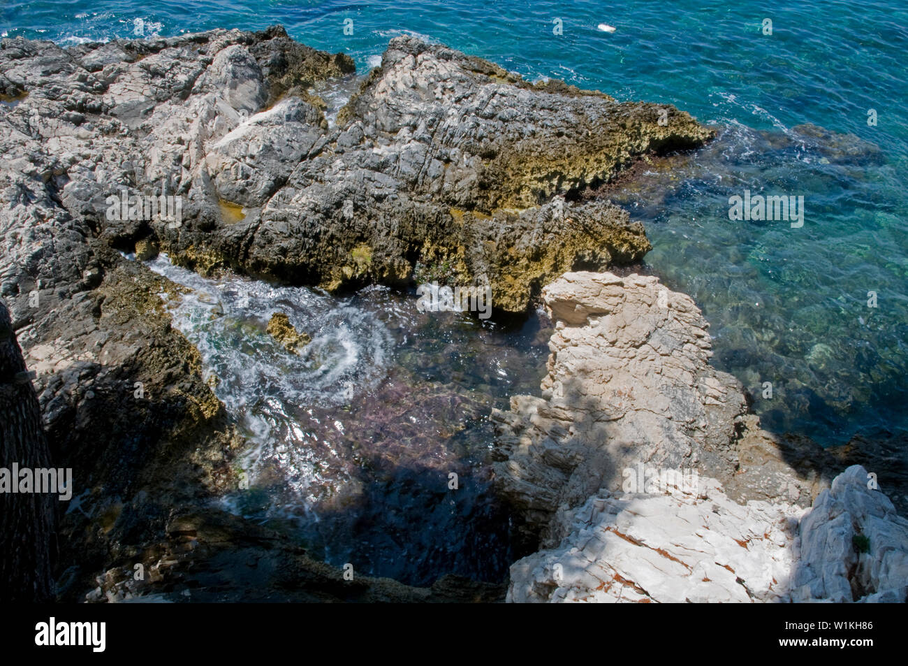 Acquamarina turbinii di acqua intorno alle rocce su una penisola nel mare Adriatico vicino a Cavtat, Croazia. Foto Stock